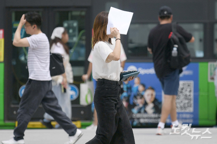 한 시민이 서류로 햇살을 가리며 발걸음을 옮기고 있다. 박종민 기자