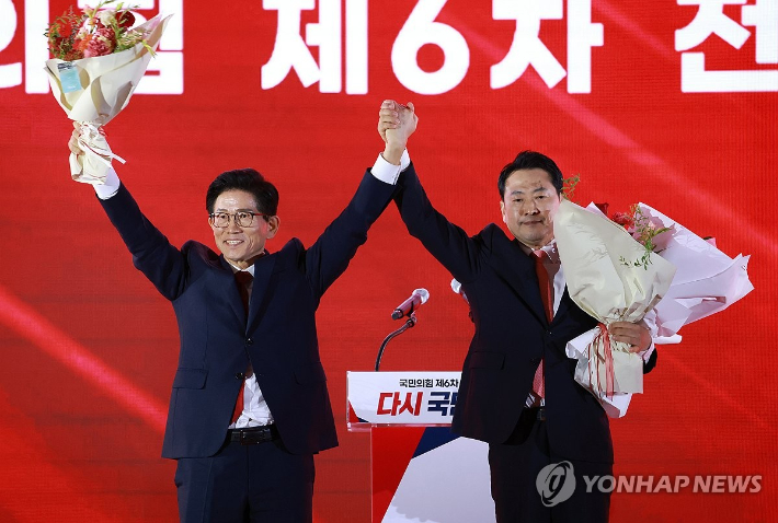 (청주=연합뉴스) 황광모 기자 = 22일 충북 청주시 흥덕구 청주오스코에서 열린 국민의힘 제6차 전당대회에서 결선에 진출한 김문수, 장동혁 당대표 후보가 꽃다발을 받은 뒤 맞잡은 손을 들어 올리고 있다. 2025.8.22 [공동취재] hkmpooh@yna.co.kr 연합뉴스