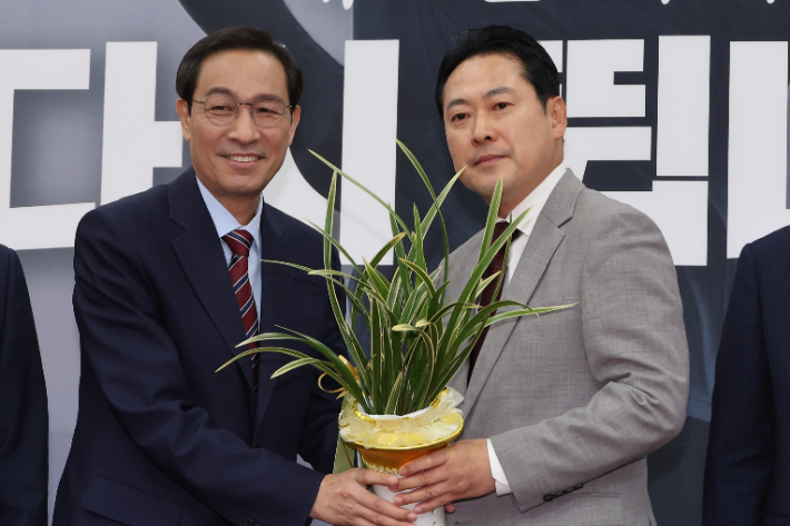 우상호 대통령실 정무수석이 27일 서울 여의도 국회에서 국민의힘 장동혁 신임 대표를 예방해 이재명 대통령이 보낸 축하난을 전달하는 모습. 연합뉴스