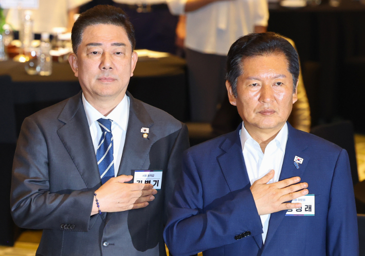 더불어민주당 정청래 대표(오른쪽)와 김병기 원내대표가 28일 인천시 중구 파라다이스시티 컨벤션에서 열린 민주당 의원단 워크숍에서 국기에 경례하고 있다. 연합뉴스