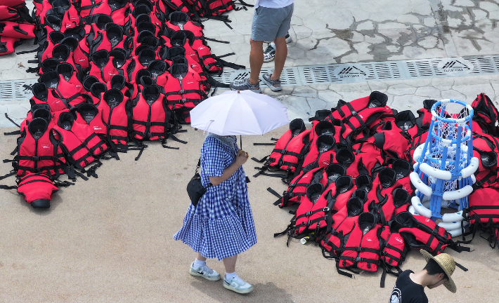 더위가 이어진 28일 대구 신천 물놀이장에서 폐장 후 구명조끼 정리가 한창인 가운데 한 시민이 양산을 쓰고 이동하고 있다. 연합뉴스