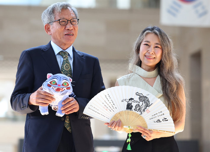 유홍준 국립중앙박물관장(왼쪽)과 넷플릭스 애니메이션 '케이팝 데몬 헌터스'의 메기 강 감독이 21일 서울 용산구 국립중앙박물관에서 선물을 주고 받은 뒤 기념촬영을 하고 있다. 연합뉴스