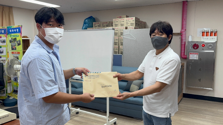 충남 홍성군에서 시행하고 있는 '찾아가는 민생 회복 소비 쿠폰' 제도로 홍성군청 홍석창 담당(왼쪽)이 홍성정신요양원 김영조 시설장(오른쪽)에게 생활인들의 쿠폰을 모아 전달하고 있다. 자료사진