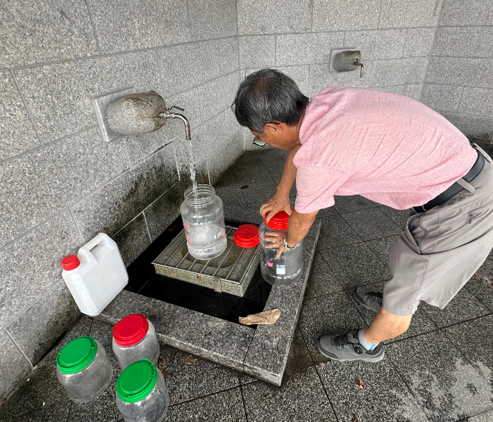지난 30일 강원 강릉시 대관령샘터에서 시민이 물통에 식수를 받고 있다. 롯데칠성음료에서 운영하는 대관령샘터는 대관령 지하 암반수를 취수해 수처리 과정을 거쳐 시민에게 식수를 제공하고 있다. 연합뉴스