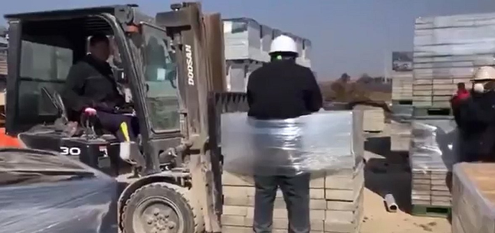 노동자가 이주노동자 A씨를 비닐로 벽돌에 묶어 지게차로 옮기는 모습과 이 모습을 보고 웃으며 휴대전화로 촬영하는 다른 노동자의 모습. 광주전남이주노동자네트워크 제공