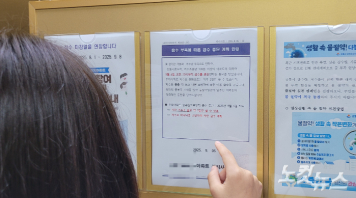 엘리베이터에 부착된 급수 중단 계획 안내문을 보고 있는 주민. 전영래 기자