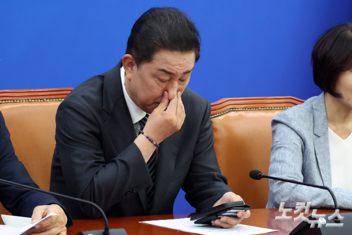 더불어민주당 김병기 원내대표가 11일 서울 여의도 국회에서 열린 정책조정회의에서 스마트폰을 확인하며 손으로 얼굴을 만지고 있다. 윤창원 기자