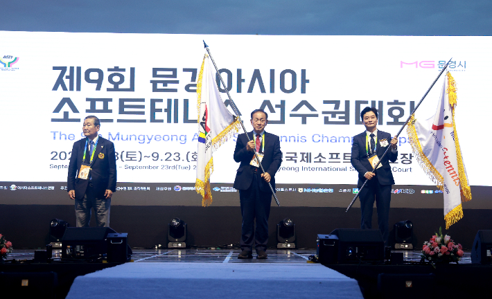 제9회 문경아시아소프트테니스선수권대회 개회식에서 안도 아시아연맹 회장(왼쪽부터)에게 대회 기를 받은 신현국 문경시장, 정인선 대한소프트테니스협회장이 대회 개막 세리머니를 펼치고 있다. 협회