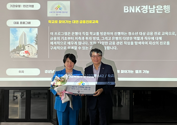 BNK경남은행 김경옥 상무(왼쪽)가 창원교육지원청 교육지원국 조의래 국장으로부터 '교육기간 진로체험 인증기관패'를 받고 있다. BNK경남은행 제공 