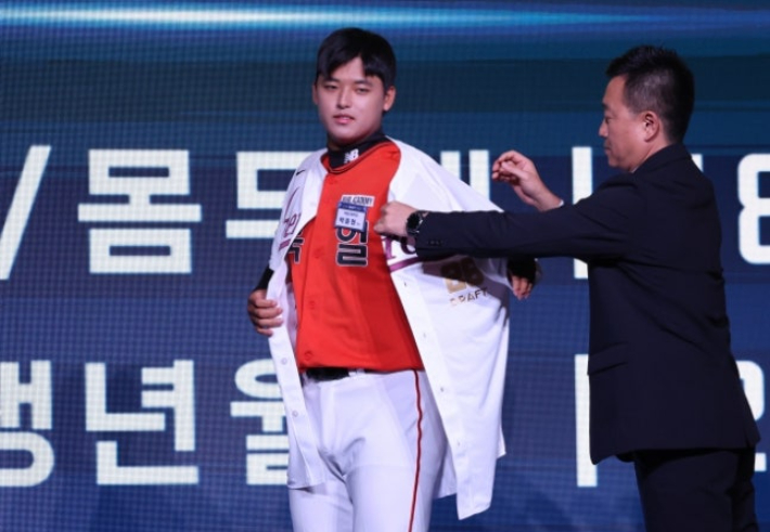 지난 17일 서울 송파구 롯데호텔 월드에서 열린 2026 KBO 신인 드래프트에서 키움 히어로즈에 1라운드 1순위 지명을 받은 천안북일고 오른손 투수 박준현(사진 왼쪽)이 유니폼을 입고 있다. 연합뉴스