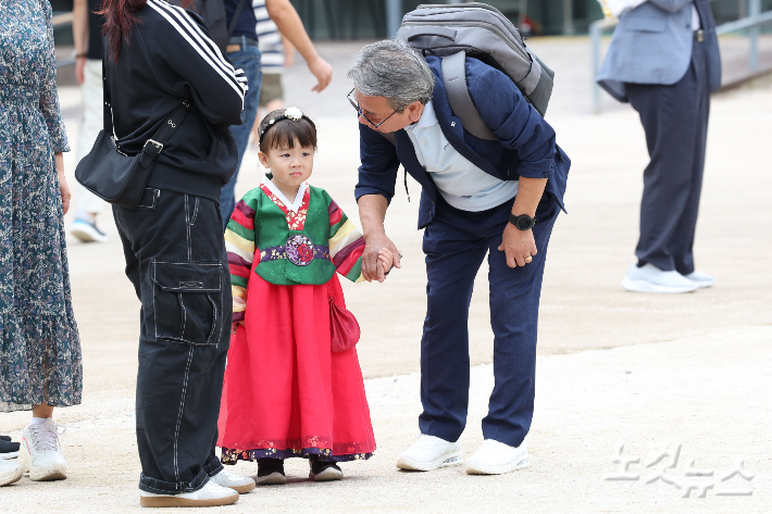 추석 연휴 한복을 입은 아이가 조부모님 손을 잡고 즐거운 시간을 보내고 있다. 류영주 기자