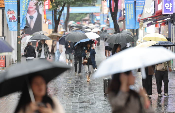 28일 비가 내리는 서울 중구 명동거리에서 시민 및 외국인관광객들이 우산을 쓴 채 걸어가고 있다. 연합뉴스