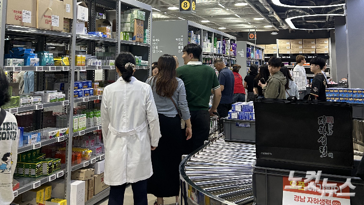 흰 가운을 입은 약사가 진열대 앞에서 시민들의 약 선택을 돕고 있다. 김한영 기자