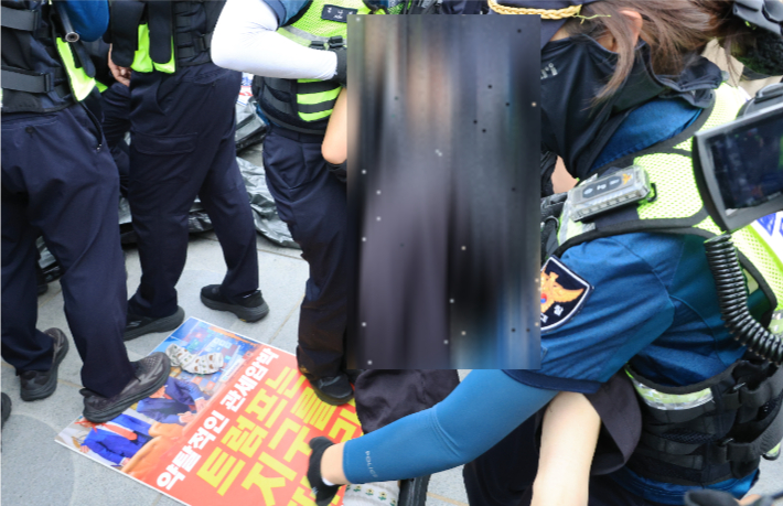 11일 서울 광화문광장에서 경찰이 '트럼프 방한 반대, 약탈적 투자 강요 규탄' 등을 주장하며 연좌시위를 벌이던 한국대학생진보연합 회원들을 해산 및 이동조치 하고 있다. 연합뉴스