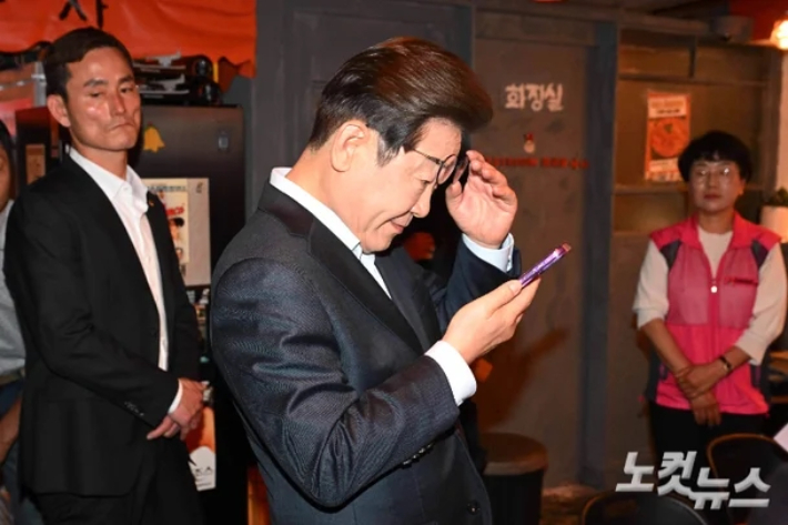 이재명 당시 더불어민주당 대선 후보가 지난 5월 1일 서울 종로구의 한 음식점에서 열린 비전형 노동자 간담회 종료 후 당 관계자에게 전달받은 휴대전화를 확인하고 있다. 대법원 전원합의체는 이날 이재명 당시 대선 후보에게 무죄를 선고한 원심판결을 파기하고 사건을 서울고법으로 돌려보냈다. 황진환 기자