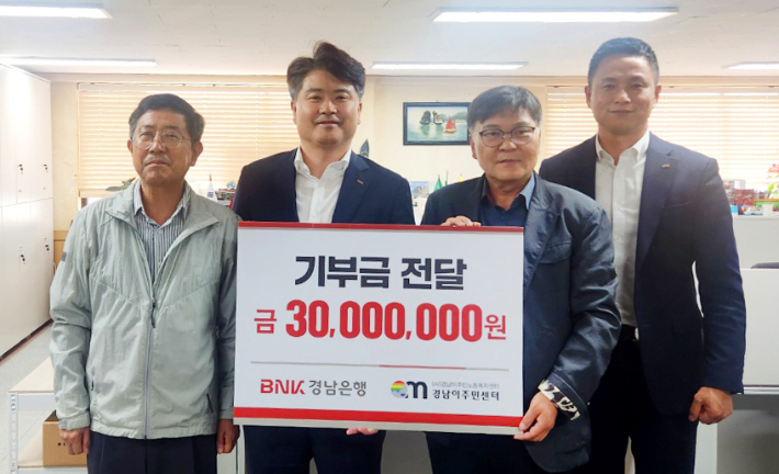 BNK경남은행 홍응일 상무(왼쪽에서 두번째)가 (사)경남이주민노동복지센터 이철승 대표에게 '기부금 기탁 증서'를 전달하고 있다. BNK경남은행 제공