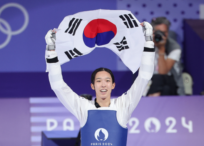 지난해 8월 8일(현지시간) 프랑스 파리 그랑팔레 태권도경기장에서 열린 2024 파리올림픽 태권도 여자 57kg급 결승에서 한국의 김유진이 이란의 나히드 키야니찬데를 꺾고 금메달을 확정한 뒤 태극기를 들고 환호하고 있다. 연합뉴스