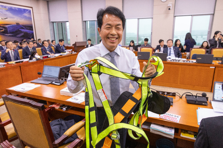 진보당 윤종오 의원이 지난 13일 국회에서 열린 2025년도 국토교통위원회 국정감사에서 건설 현장용 안전 장구를 입고 질의를 마친 뒤 국감장에서 장구를 벗은 뒤 들어 보이고 있다. 연합뉴스