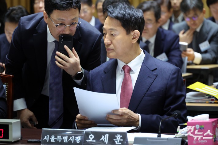 오세훈 서울시장이 23일 서울 중구 서울시청에서 열린 국회 행정안전위원회의 서울시에 대한 국정감사에서 관계자와 대화를 하고 있다.