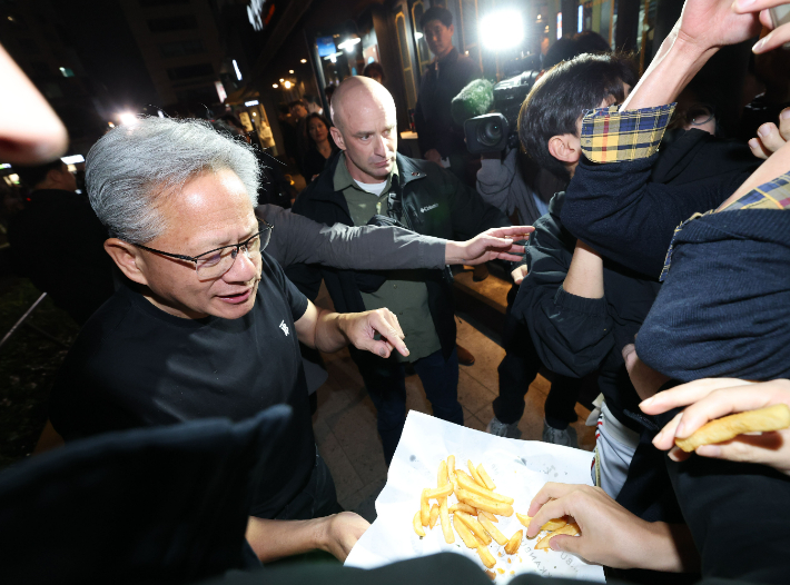 젠슨 황 엔비디아 최고경영자가 30일 서울 삼성동 한 치킨집에서 진행된 이재용 삼성전자 회장, 정의선 현대차그룹 회장과 치맥 회동 중 시민에게 치킨과 감자튀김을 나눠주고 있다. 연합뉴스
