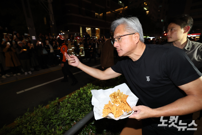 젠슨황 엔비디아 최고경영자가 30일 이재용 삼성전자 회장, 정의선 현대자동차그룹 회장과 서울 강남구 깐부치킨 매장에서 치킨 회동 중 밖으로 나와 시민들에게 치킨 등을 나눠주고 있다. 류영주 기자