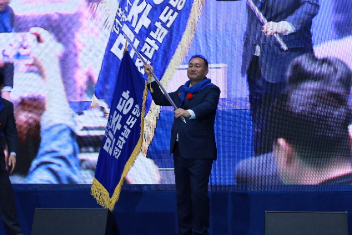 더불어민주당 전남도당 위원장 선거에 단독 출마한 김원이 국회의원(전남 목포시)이 2일 나주 종합스포츠파크 다목적체육관에서 전남도당 제2차 임시당원대회에서 열린 민주당 전남도당 새 전남도당 위원장으로 선출된 후 도당 깃발을 흔들고 있다. 더불어민주당 전남도당 제공