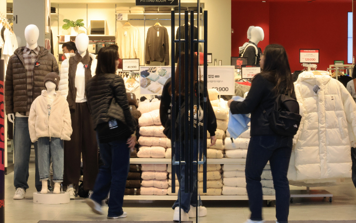 지난달 26일 서울 명동 상점의 쇼윈도에 겨울 의류가 전시되어 있는 가운데 시민들이 쇼핑하고 있다. 연합뉴스