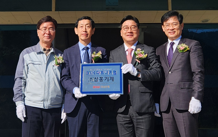 BNK경남은행 허종구 부행장(사진 오른쪽 두번째)과 ㈜삼홍기계 김홍범 대표 등이 파트너기업 현판 앞에서 기념촬영을 하고 있다. BNK경남은행 제공 