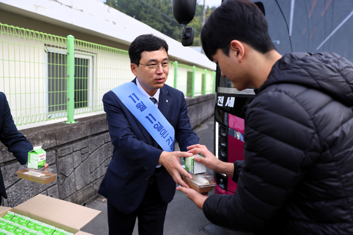 류길년 경남농협 본부장이 등굣길 학생들에게 우리 쌀로 만든 따끈한 가래떡과 신선한 우유를 전달하고 있다. 경남농협 제공 