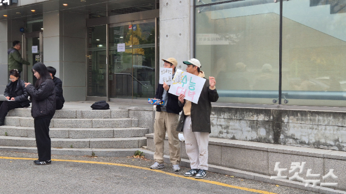 왈리(41)씨와 황모(35)씨가 '수능대박', '초코바 먹고 힘내'라고 적힌 손팻말을 들고 수험생들에게 초콜릿바를 나눠주고 있다. 송선교 기자