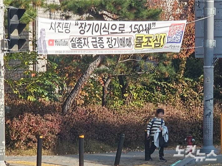 13일 오후 일산서구의 한 학원가에 '시진핑 장기이식으로 150세, 실종자 급증 장기매매 몸조심!'이라는 내용의 현수막이 달려 있다. 그 앞을 초등학생이 지나고 있는 모습. 이원석 기자