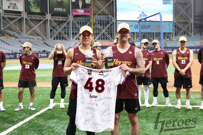 웰스(사진 앞줄 오른쪽)가 지난 7월 23일 서울 구로구 고척스카이돔에서 키움 주장 송성문으로부터 선수단의 친필 사인이 담긴 유니폼을 받고 있다. 이날 키움은 웰스 송별 행사를 했다. 키움 히어로즈 제공 