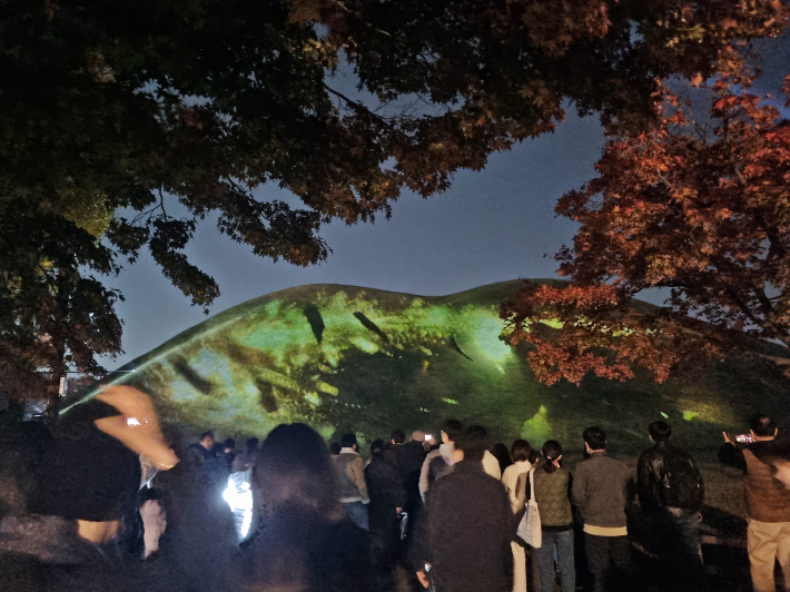 대릉원 일원에서 열린 '2025 국가유산 미디어아트 경주 대릉원' 행사에서 관람객들이 고분에 투사된 미디어아트 영상을 감상하고 있다. 경주시 제공