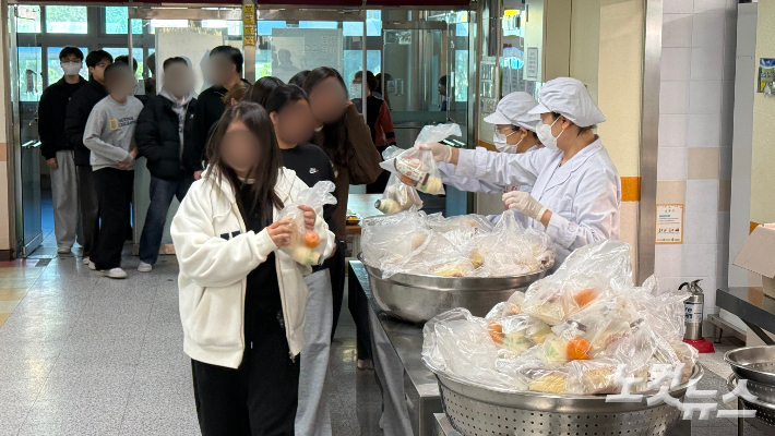 학교 비정규직 노조 파업으로 급식이 중단된 가운데 광주의 한 중학교에서 급식봉사자들이 학생들에게 빵·우유·과일 등이 담긴 대체식을 나눠주고 있다. 김한영 기자