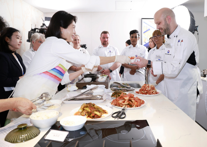 김혜경 여사가 22일(현지시간) 남아프리카공화국 요하네스버그 주남아공한국문화원에서 열린 한-남아공 음식문화 만남 행사에서 참가자에게 음식을 떠주고 있다. 연합뉴스