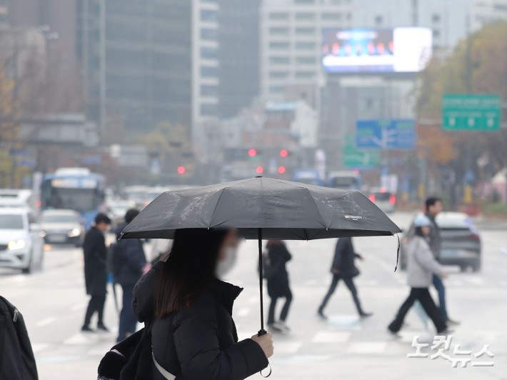 황사비가 내린 25일 오전 서울 중구 세종대로 사거리에서 우산을 쓴 시민들이 발걸음을 재촉하고 있다.