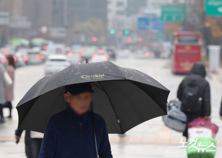 황사비가 내린 25일 오전 서울 중구 세종대로 사거리에서 우산을 쓴 시민들이 발걸음을 재촉하고 있다.