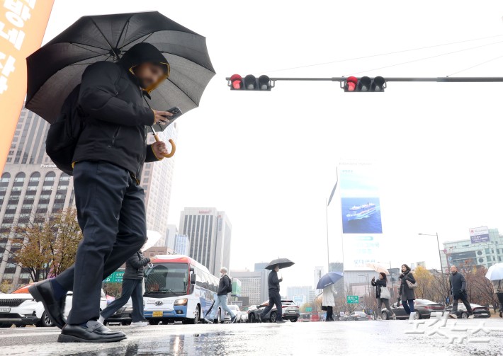 황사비가 내린 25일 오전 서울 중구 세종대로 사거리에서 우산을 쓴 시민들이 발걸음을 재촉하고 있다.