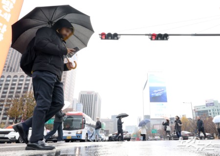 황사비가 내린 25일 오전 서울 중구 세종대로 사거리에서 우산을 쓴 시민들이 발걸음을 재촉하고 있다.