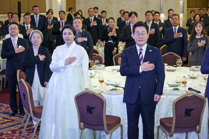 튀르키예를 국빈 방문 중인 이재명 대통령과 김혜경 여사가 25일(현지시간) 앙카라의 한 호텔에서 열린 동포·지상사 간담회에서 국기에 경례하고 있다. 연합뉴스