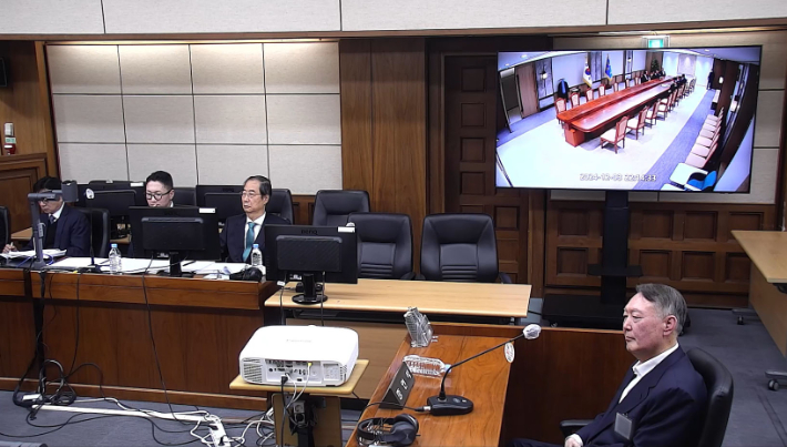 윤석열 전 대통령이 지난달 19일 서울 서초구 서울중앙지방법원에서 열린 한덕수 전 국무총리의 내란 재판에 증인으로 출석해 증거 CCTV 영상을 지켜보고 있다. 연합뉴스