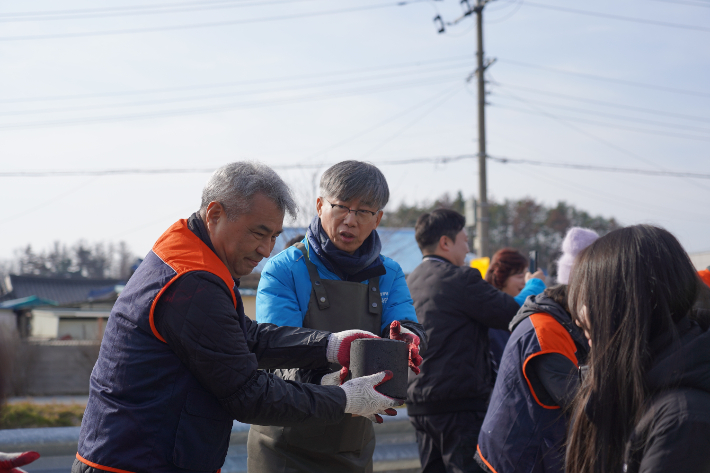 조성돈 한국원자력환경공단 이사장(왼쪽 두번째)이 따뜻한 겨울나기 사랑나눔 행사에서 연탄을 나르고 있다. 공단 제공