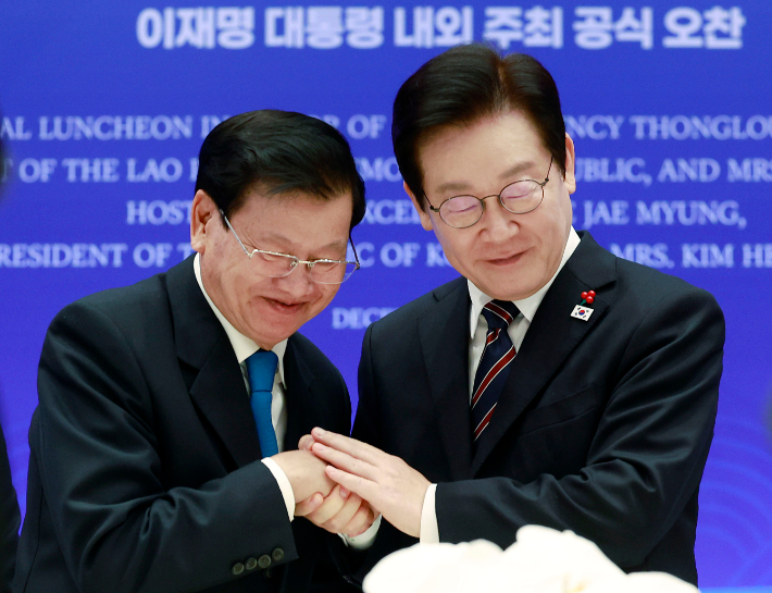 이재명 대통령이 15일 용산 대통령실에서 열린 한-라오스 공식오찬에서 통룬 시술릿 라오스 국가주석과 건배 후 손을 맞잡고 있다. 연합뉴스
