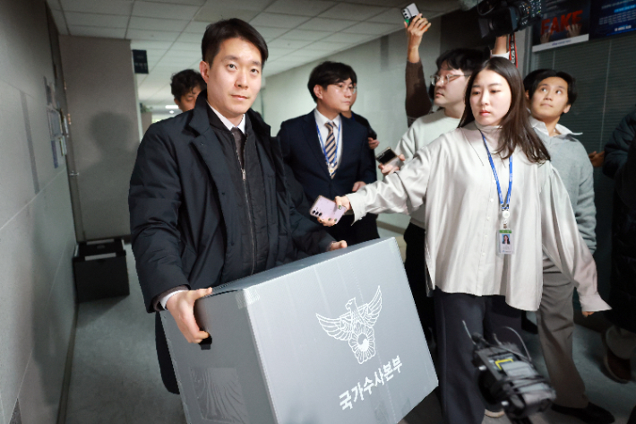 통일교 금품 수수 의혹과 관련해 압수수색을 하는 경찰 관계자들이 압수품을 옮기고 있다. 연합뉴스