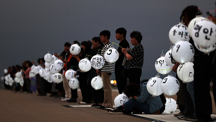 추석 당일이던 지난 10월 6일 전남 무안군 무안국제공항 활주로에서 열린 12·29 제주항공 여객기 참사 유가족 협의회의 추모행사에서 한 유가족이 유등을 들고 오열하고 있다. 연합뉴스