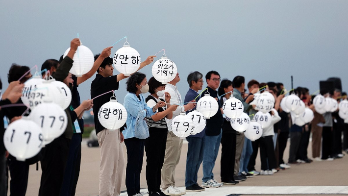 추석 당일이던 지난 10월 6일 전남 무안군 무안국제공항 활주로에서 열린 12·29 제주항공 여객기 참사 유가족 협의회의 추모행사에서 유가족들이 유등을 들고 있다. 연합뉴스
