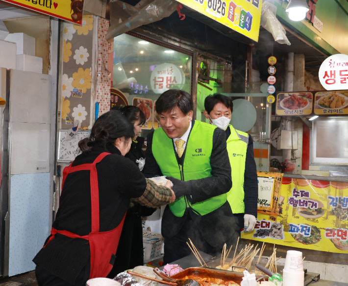 23일 최재호 창원상의 회장이 명서전통시장 상인들에게 떡을 나눠주고 있다. 창원상의 제공