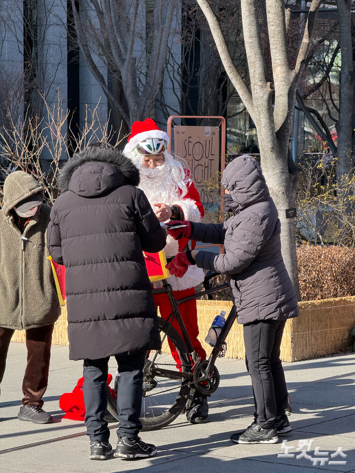 25일 오후 한 산타 분장을 한 남성이 시민들에게 인사와 기념품을 건네고 있다. 김태헌 기자