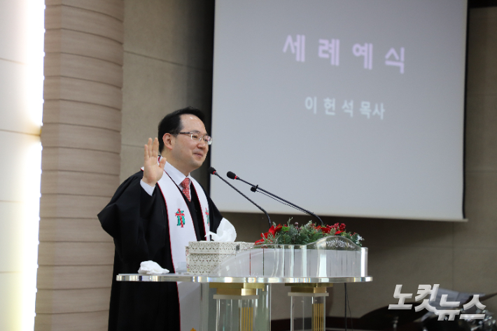 세례예식 집례하고 있는 이헌석 담임목사. 김일현 선교국장 