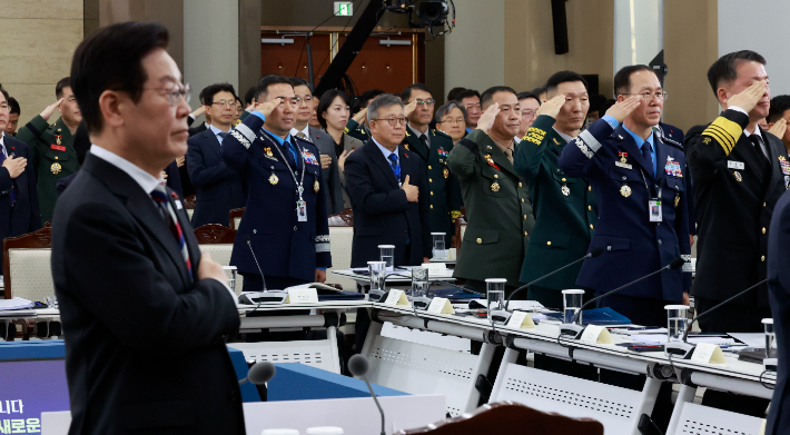 18일 서울 용산구 국방부에서 열린 국방부·국가보훈부 업무보고에서 이재명 대통령을 비롯한 참석자들이 국기에 경례하고 있다. 연합뉴스